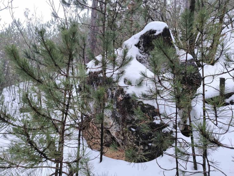 Magányos, hóval borított szikla az út mellett